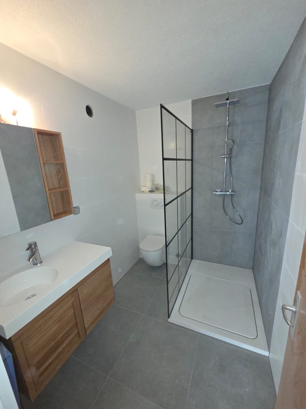 Salle de bain réalisée par GRD : douche à l'italienne avec paroi style verrière, WC suspendu et meuble vasque en bois